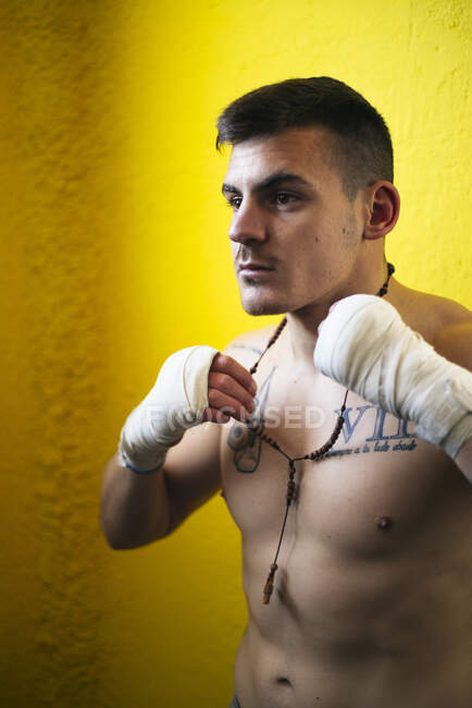 Muscular fighter with bandage arms putting on cross pendant. — Stock Photo