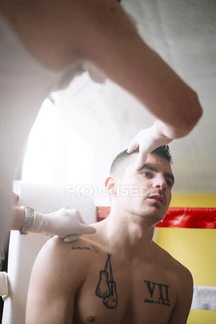 Mani di medico irriconoscibile che controllano l'occhio del pugile sul ring. — Foto stock