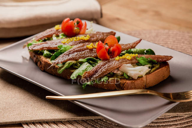 Sandwich mit Gemüse und Fisch auf grauem Teller mit Gabel — Stockfoto