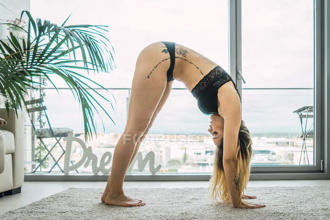 Young woman in black underwear stretching at home in morning — Stock Photo