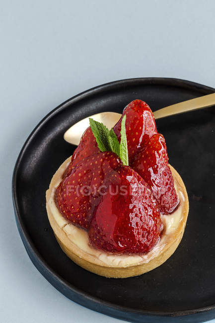 Delicious dessert filled with cream and fresh strawberries on plate on blue background — Stock Photo
