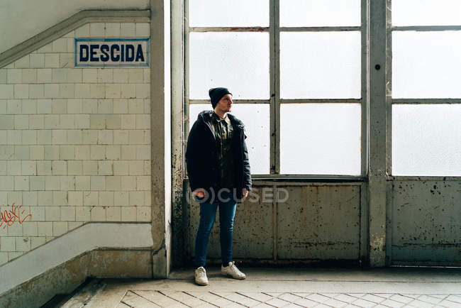 Homme adulte debout à la fenêtre près des escaliers dans le hall d'entrée — Photo de stock