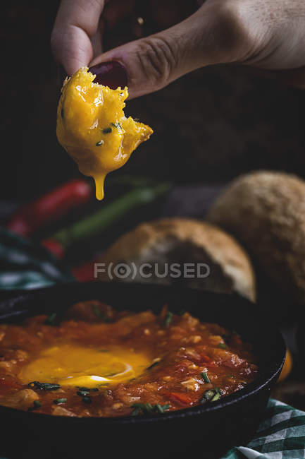 Mão humana sobre ovo frito com tomate, pimentas vermelhas e pão na frigideira — Fotografia de Stock