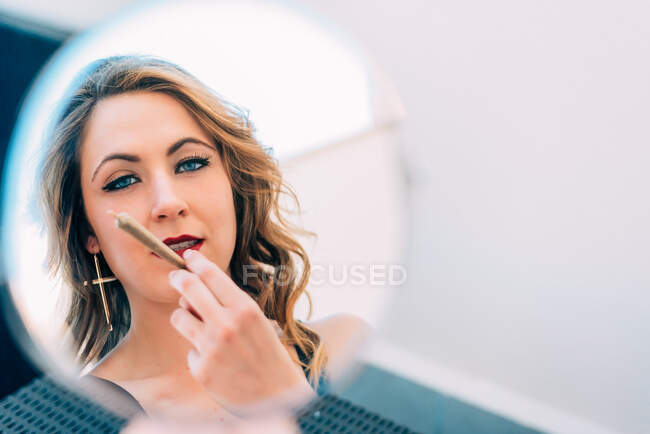 Jeune femme fumant un joint de cannabis dans le miroir — Photo de stock