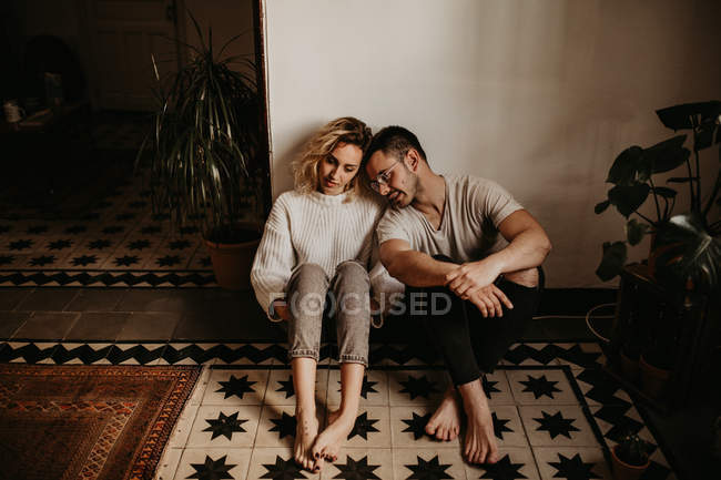 Romántico hombre y mujer sentado en el suelo en casa juntos - foto de stock