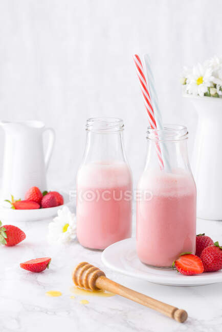 Milkshake de fresa rosa servido en botellas con paja. - foto de stock
