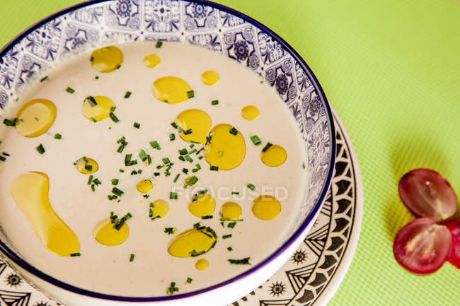 Close-up of cream soup with oil in patterned bowl on green napkin — Stock Photo