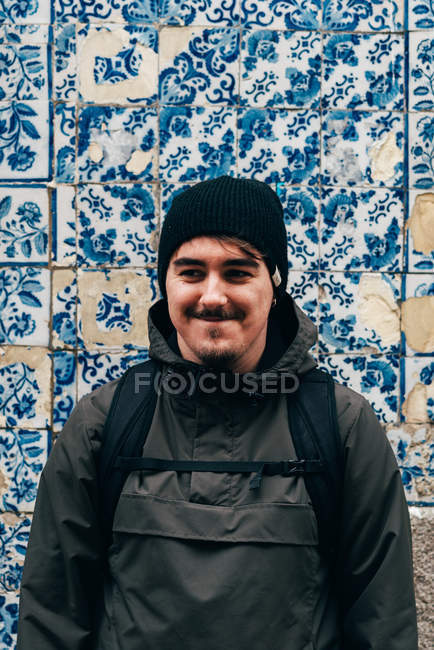 Веселий турист стоїть біля стіни з блакитною плиткою — стокове фото