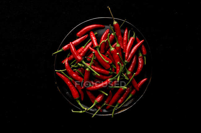 Pan of red hot peppers on black background — Stock Photo