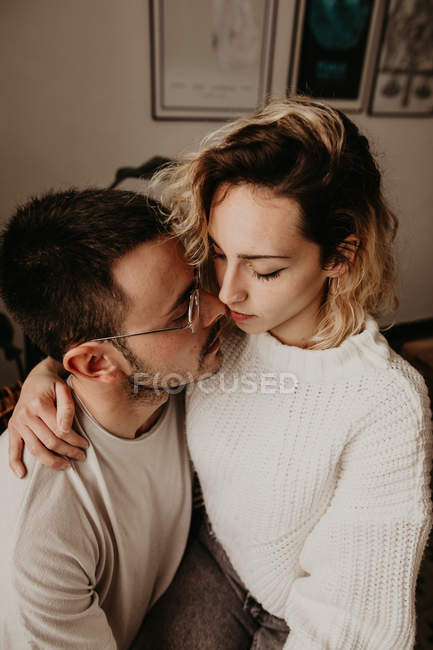 Heureux homme et femme assis et embrassant à la maison ensemble — Photo de stock