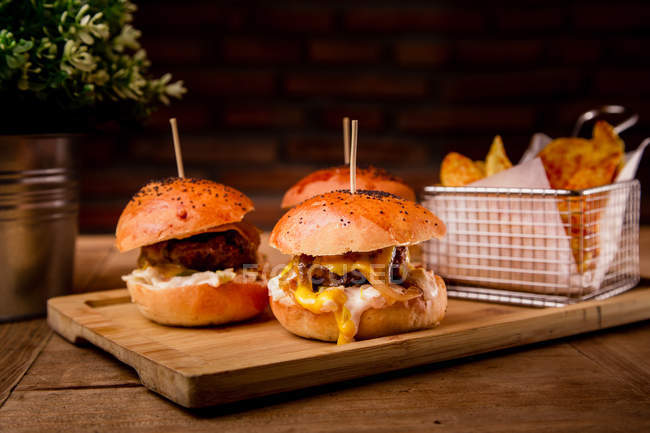 Tasty burgers and french fries in served on wooden tray — Stock Photo