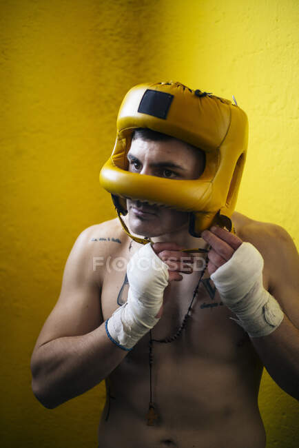 Боксер без рубашки надевает шлем для боя. — стоковое фото