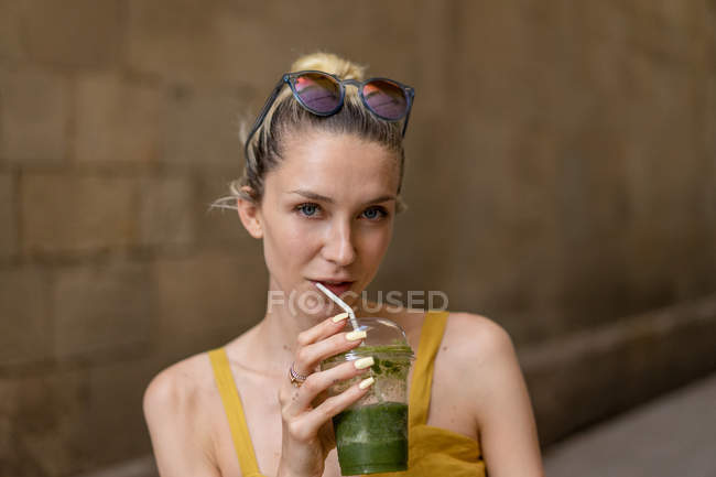 Portrait of smiling woman in summer dress standing with drink — Stock Photo