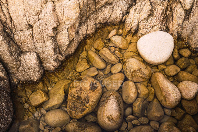 Dall'alto pietre marroni ruvide grandi che posano nell'acqua. — Foto stock