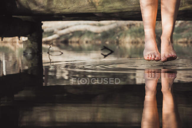 Weibliche Beine über Fluss im Wald — Stockfoto