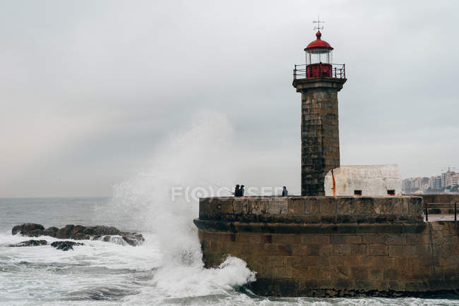 Beacon tower on pier at wavy ocean, Porto, Portugal — Stock Photo