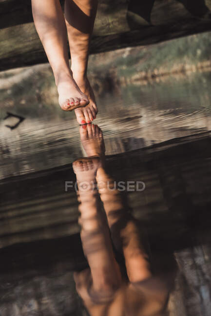Piernas femeninas sobre el río en el bosque - foto de stock