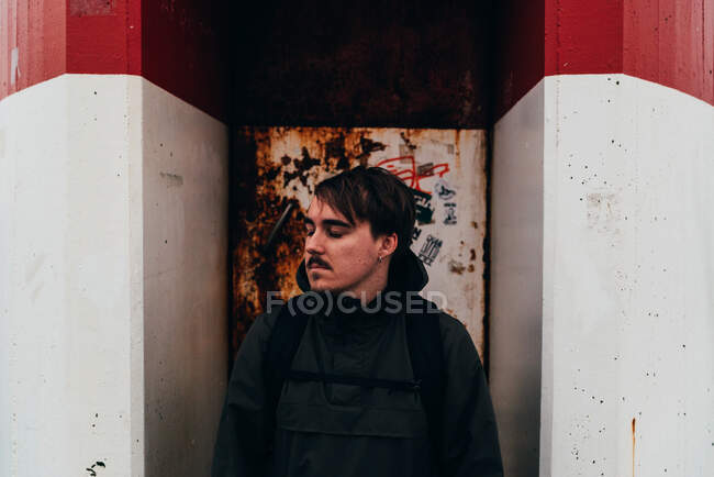 Вдумчивый человек стоит у громоздких дверей красно-белого здания. — стоковое фото