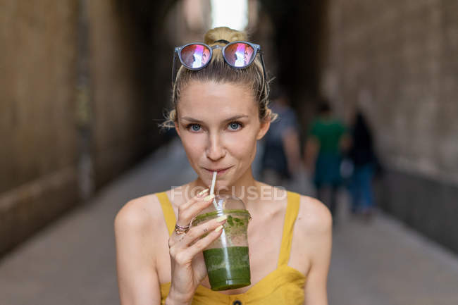 Портрет усміхненої жінки в літній сукні, що стоїть з напоєм — стокове фото
