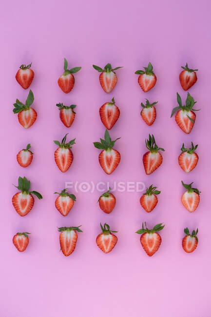 Blick von oben auf Erdbeerhälften auf rosa Hintergrund — Stockfoto