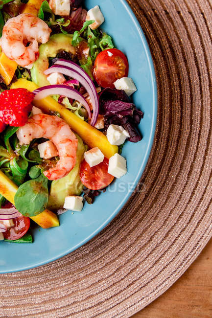Primer plano de ensalada de verduras con camarones en tazón azul en la estera - foto de stock
