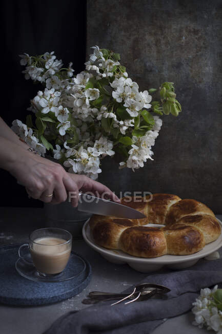 Schnitthände des Kochs schneiden den Laib Brot auf einem Teller. — Stockfoto