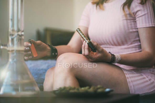 Mulher preparando maconha em um copo contundente — Fotografia de Stock