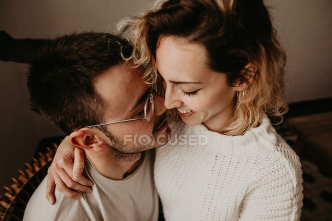 Homem e mulher felizes sentados e abraçando em casa juntos — Fotografia de Stock