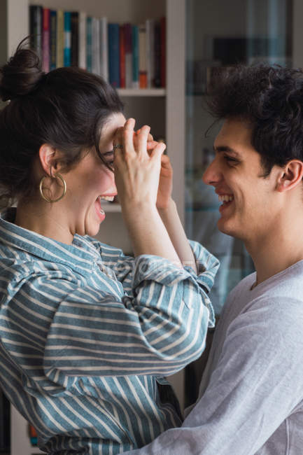 Riendo joven pareja en pijama abrazando en casa - foto de stock