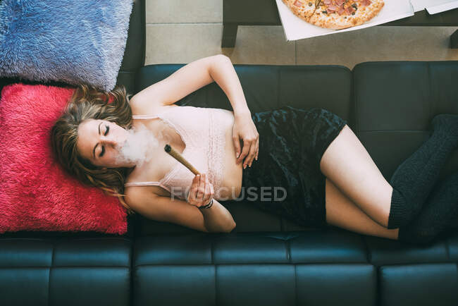 Frau liegt mit Marihuana-Joint auf Sofa — Stockfoto
