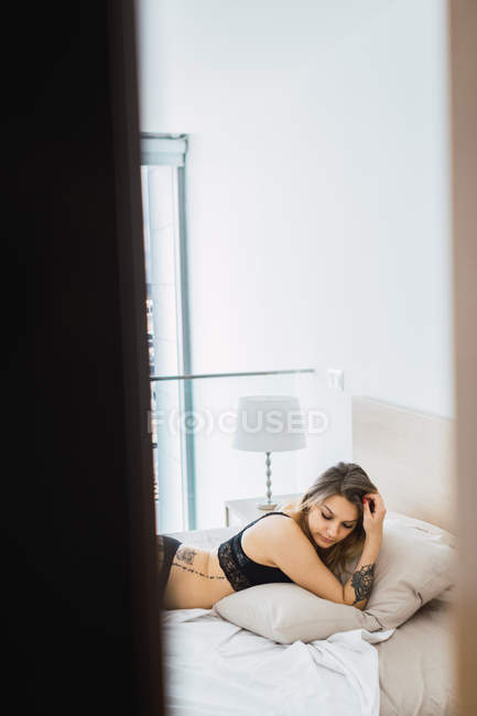 Sedutor mulher no preto lingerie deitado no cama — Fotografia de Stock