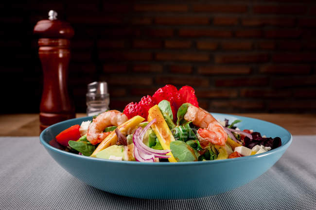 Salada de legumes com camarões em tigela azul na superfície cinza — Fotografia de Stock