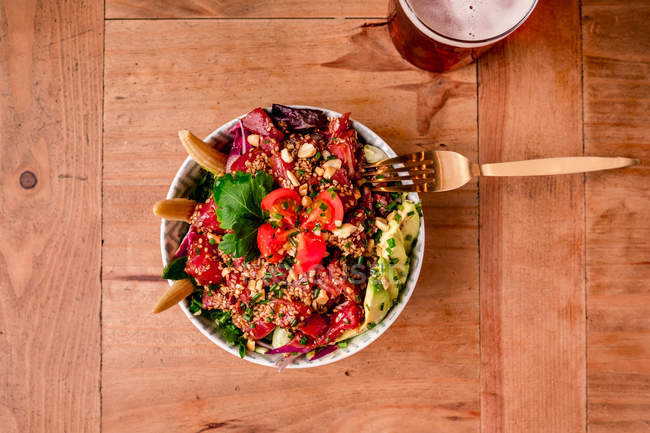 Schüssel mit leckerem Gemüsesalat mit Avocado auf Holztisch — Stockfoto