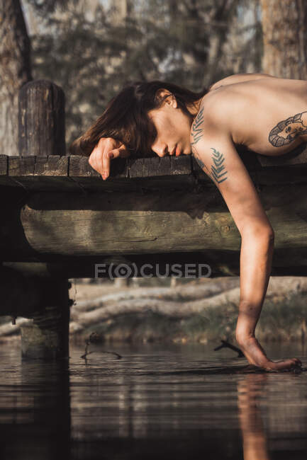 Mulher nua deitado e tocando água — Fotografia de Stock
