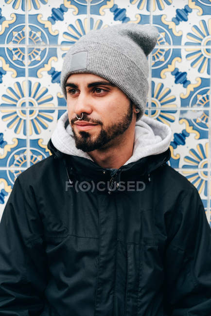 Retrato de turista masculino pensativo em pé na parede com azulejos azuis — Fotografia de Stock