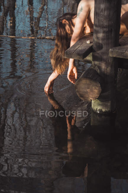 Голая женщина лежит и трогает воду — стоковое фото