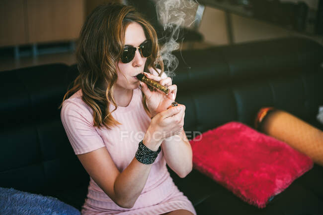 Mulher fumando maconha em um copo contundente — Fotografia de Stock