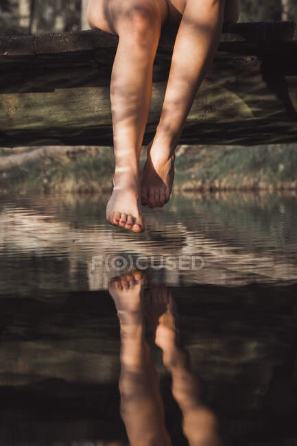Women naked feet with red pedicure moving on wooden pier up water — Stock Photo