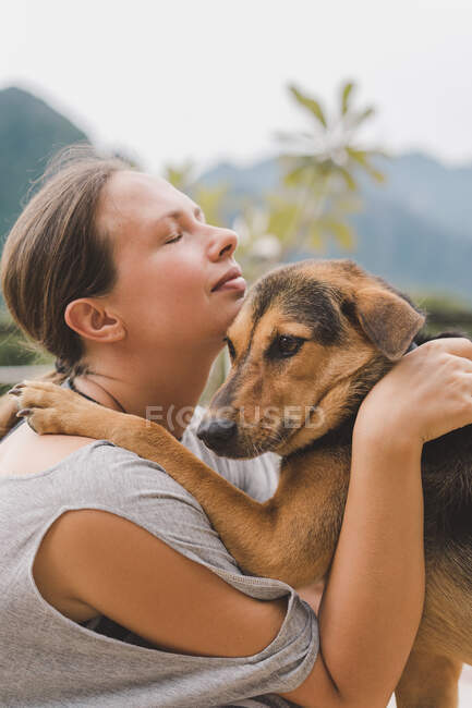 Mulher acariciando cão na encosta — Fotografia de Stock