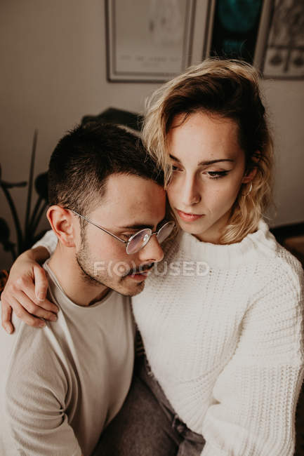 Nachdenkliche Mann und Frau sitzen und umarmen sich zu Hause zusammen — Stockfoto