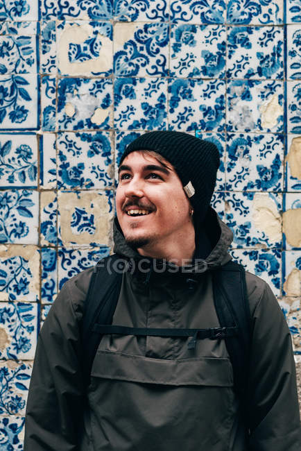 Turista alegre homem de pé na parede com azulejos azuis — Fotografia de Stock
