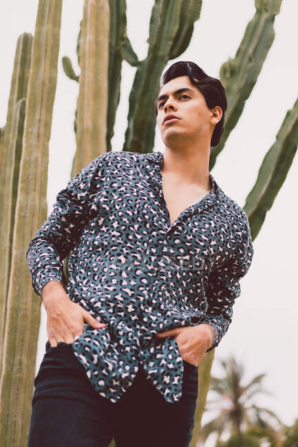 Junger Mann steht am Kaktus — Stockfoto