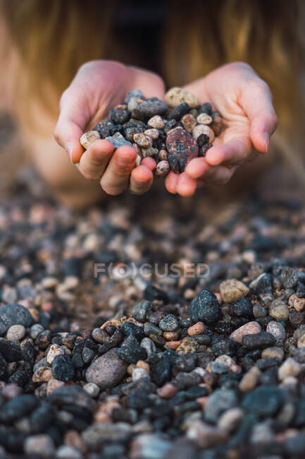 Crop unrecognizable person holding handful of pebble. — Stock Photo