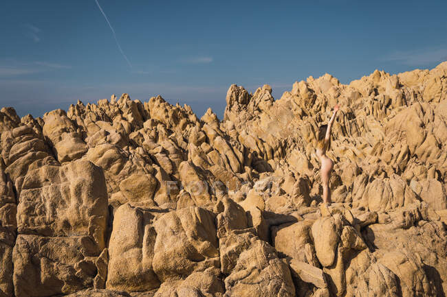 Vista laterale di donna nuda attraente irriconoscibile in piedi sulla roccia nella giornata di sole. — Foto stock