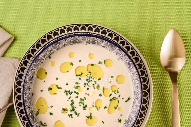 Close-up of cream soup with oil in patterned bowl on green napkin — Stock Photo
