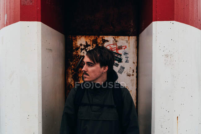 Thoughtful man standing at grungy door of red and white building. — Stock Photo
