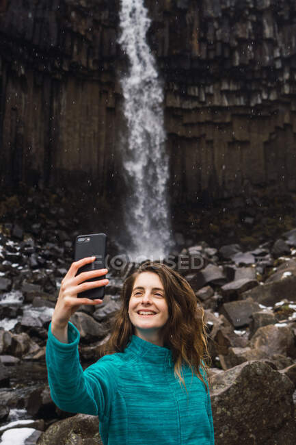 Frau macht Selfie in der Nähe von Wasserfall — Stockfoto