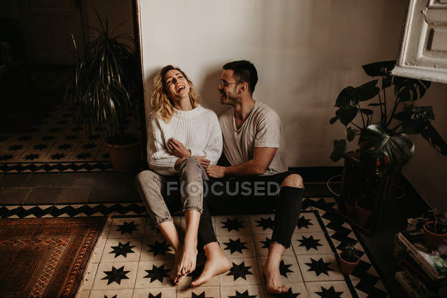Homem romântico e mulher sentados no chão em casa juntos — Fotografia de Stock