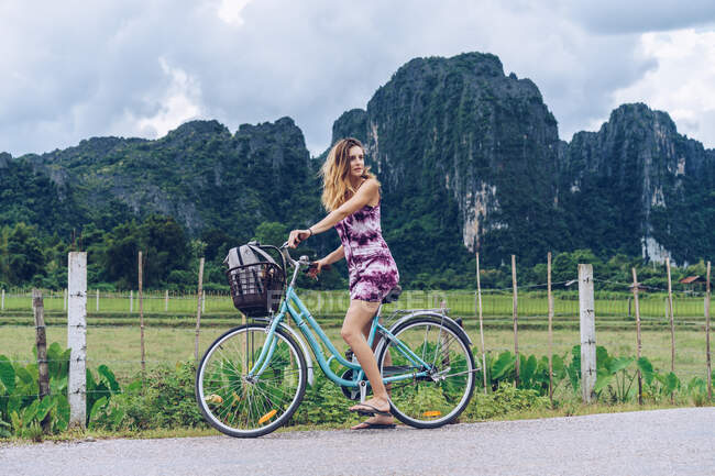 Hübsche Frau mit Fahrrad auf Landstraße — Stockfoto