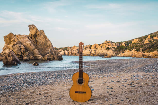 Класична акустична гітара розміщена на піщаному пляжі в океані . — стокове фото